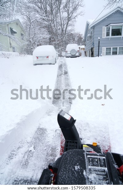 snow blower removing snow on driveway after snow storm  \
         