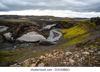 A snow bridge crossing a glacial river on the bleak volcanic landscape as seen on the hike from Skógafoss up to the Fimmvörðuháls hut and pass, south Iceland - Shutterstock ID 2155108821