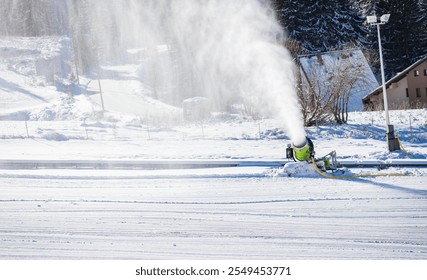 A snow cannon producing artificial snow in a winter resort setting. The machine sprays misty snow against a backdrop of snowy trees, creating a dynamic and frosty winter atmosphere. - Powered by Shutterstock