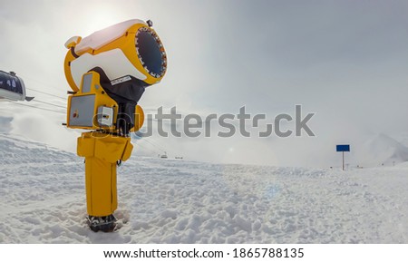 snow cannon in sunny on the background of mountains and cable car.