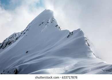 Snow capped mountain summit in the clouds