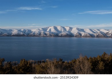 snow capped mountains on lake sevan in clear weather at sunset - Powered by Shutterstock