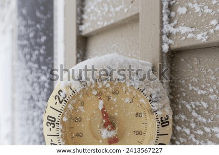 Snow Capped Thermometer Mounted on Wooden Siding of House Showing Freezing Temperatures