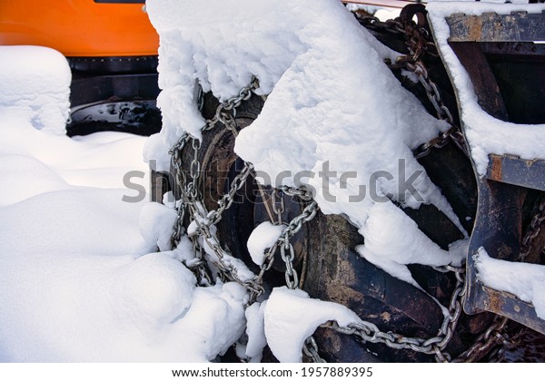 Snow\
chain on an excavator tire standing in the\
forest