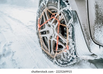 Snow chains on tire. Car wheel with traction chains on a snowy winter road