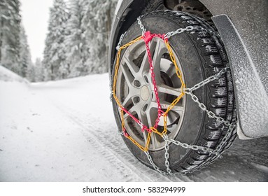Snow chains on tire. Detail of wheel in winter forest