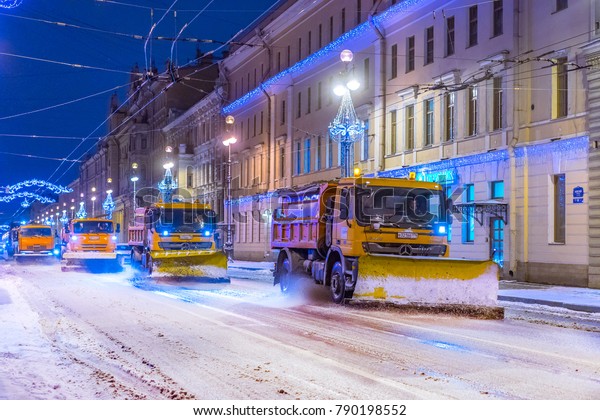 Snow cleaning. A column of\
cars cleans the snow from the streets of the city. Snow-removing\
machines. Cleaning roads from snow in St. Petersburg. Russia.\
08.01.2018
