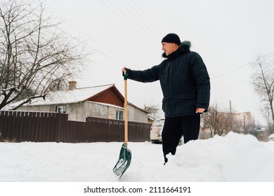 Snow Collapse. Senior Man Cleaning Snow At Winter Weather With A Shovel On A Yard During The Cold Day. Winter Trouble Concept