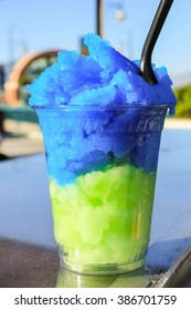 Snow Cone In Blue And Green Color In Plastic Cup.