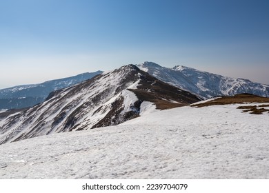 Snow covered alpine pasture with panoramic view on snow capped mountain ridges of summit Zirbitzkogel and Kreiskogel in Seetal Alps, Styria, Austria, Europe. Hiking trail Central Alps in sunny winter