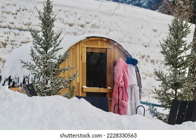 Snow covered barrel sauna with bathrobes 