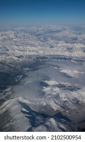 Snow Covered Canadian Rocky Mountains Viewed From Airplane Window Flying Over The Rockies In November High Snow Covered Peaks With Low Lying Clouds Making Shadows As Seen From Above In Transit In Air