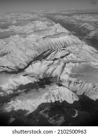 Snow Covered Canadian Rocky Mountains Viewed From Airplane Window Flying Over The Rockies In November High Snow Covered Peaks With Low Lying Clouds Making Shadows As Seen From Above In Transit In Air