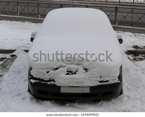 Snow covered car in\
the city in winter.