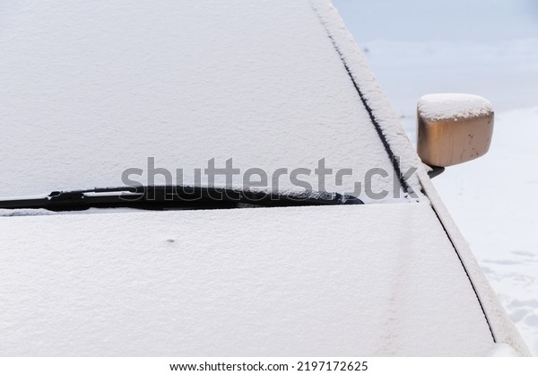 Snow covered car\
hood and windshield wipers