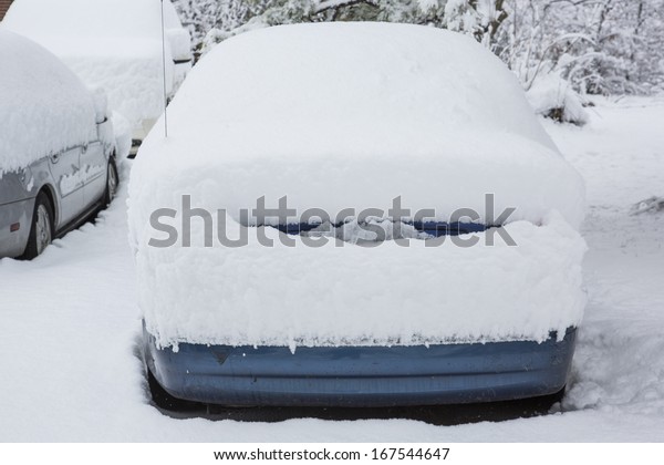Snow covered car stuck on\
road