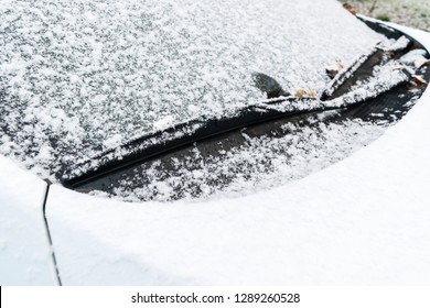 Snow Covered Car Window With Wipers, Macro, Close Up. Car Wiper Blades Clean Snow From Car Windows. Flakes Of Snow Covered The Car.