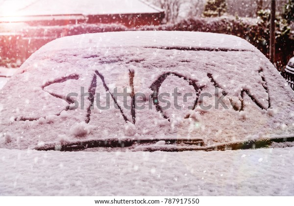 Snow covered car windscreen with the word snow\
written in the snow