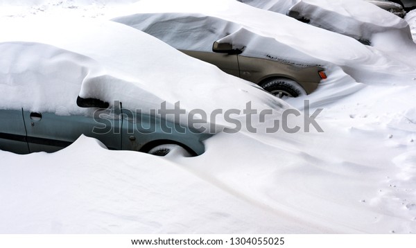 Snow covered cars after snowfall at\
winter day. The parked cars in snow. Winter urban\
scene