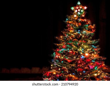 Snow Covered Christmas Tree With Multi Colored Lights At Night