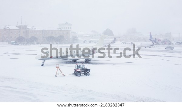 Snow covered commercial plane at the airport.\
Close-up of the plane after snowfall. Airport workers clean\
runways. Winter bad weather\
conditions.