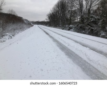 Snow covered country road in rural America showing hazardous road conditions. A slippery and dangerous icy road in the country.  Snow on farmland and Christmas time. Winter weather advisory in effect.