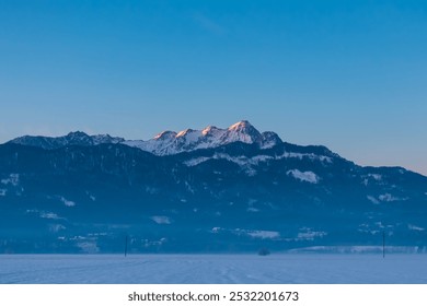 Snow covered field with panoramic sunrise view of snow-capped mountain peak Mittagskogel (Kepa) in Karawanks seen from Rosental, Carinthia, Austria. Peaceful alpine landscape. Austrian Alps in winter - Powered by Shutterstock