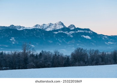 Snow covered field with panoramic sunrise view of snow-capped mountain peak Mittagskogel (Kepa) in Karawanks seen from Rosental, Carinthia, Austria. Peaceful alpine landscape. Austrian Alps in winter - Powered by Shutterstock