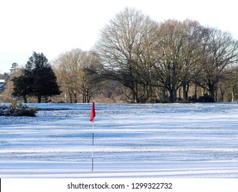 Snow covered golf course with red flag
