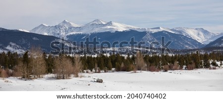Snow covered lake and mountains of central Colorado. Mountains at the edge of Lake Dillon in Colorado.  View across Dillon Reservoir in Silverthorne, Colorado.  Snowcapped mountains and green forest.