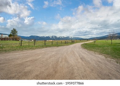 A Snow Covered Mountain Range Is Seen From A Rural Country Ranch And Dirt Road In The Small Town Of Arlee, Montana, USA