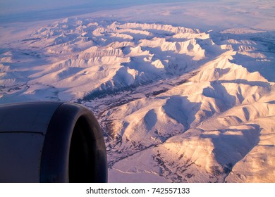 Snow Covered Mountain Ranges And Glaciers On A Commercial Airline Flight From Seattle To Anchorage. Alaska.  An Out Of Focus Jet Engine Is In Foreground.