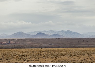 Snow Covered Mountains And Open Plains Of A Wide Open Desert Vista Landscape On Overcast Day In Rural New Mexico