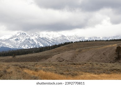 snow covered mountains in yellowstone, image shows a landscape image of the countryside, including forests at the base of the mountain and the snow covered mountain with dark clouds taken october 2023 - Powered by Shutterstock