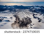 Snow covered Red Glacier in Lake Clark National Park in Alaska. Glacial ponds, crevasses, snow and ice. Red glacier is covered with ash and debris from Mount Iliamna Volcano. Cook Inlet in distance.