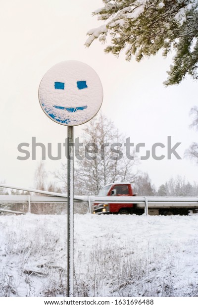 Snow\
covered road sign and emoticon drawn. Winter\
mood