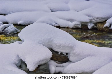 Snow Covered Rocks In Cold River Water In Winter