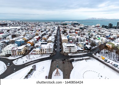 The Snow Covered Rooftops Of Reykjavik, Historic Capital City Of Iceland. Traditional Houses, Aerial View, With The Coastline, Sea And Mountains Beyond.  No Identifiable People And All Logos Removed. 