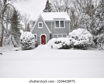 Snow covered suburban gray cottage bungalow style two story home with icicles hanging in northeastern USA winter storm