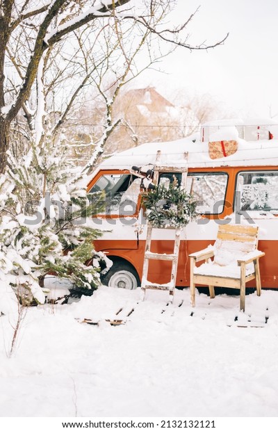 Snow covered van in winter camp, with\
Christmas decoration.