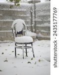 Snow covered wooden chair in the garden after heavy snowfall in winter