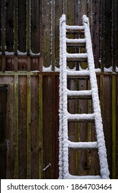 Snow Covered Wooden Ladder On The Wall Of Rustic Barn