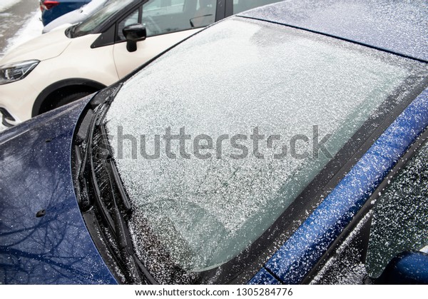 Snow covers car windshield and mirror. Concept of\
road safety in winter.