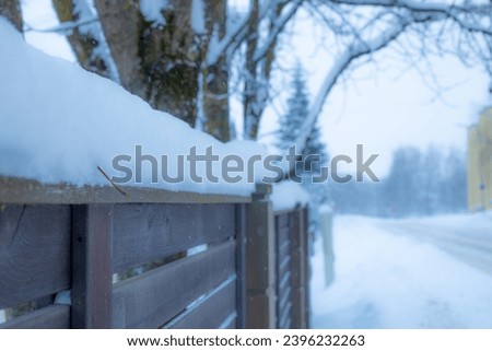 Snow covers the edge of the wooden set during winter. Winter with icy snow, snow cap, snowy ground and sunlight. Soft selective focus.