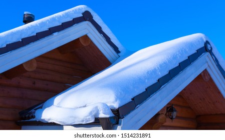 Snow Drift On Roof After Of Snowfalls On Sunny Day. Wooden House In The Snow.