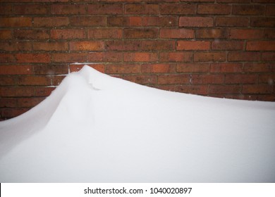 Snow Drift With Red Brick Wall In Background