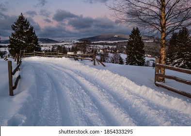 Snow drifts on road through twilight small and quiet winter alpine village, Voronenko, Carpathian, Ukraine. Night countryside hills, groves and farmlands in remote alpine village. - Powered by Shutterstock