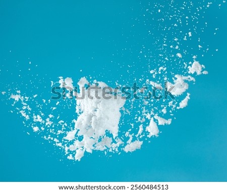 Snow dust element falling over blue sky. Fluffy White snow splash flying or throwing in mid air. Snowfall on blue background isolated