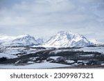 Snow engulfs Scenic Point and Rising Wolf Mountain on the Rocky Mountain Front of N. Central Montana, the Eastern part of Glacier National Park.  The sky is full of pale wispy clouds. 