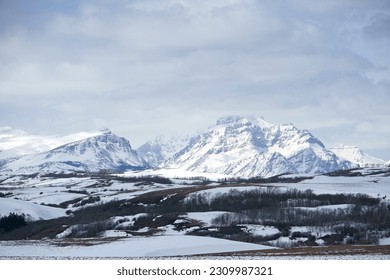 Snow engulfs Scenic Point and Rising Wolf Mountain on the Rocky Mountain Front of N. Central Montana, the Eastern part of Glacier National Park.  The sky is full of pale wispy clouds.  - Powered by Shutterstock